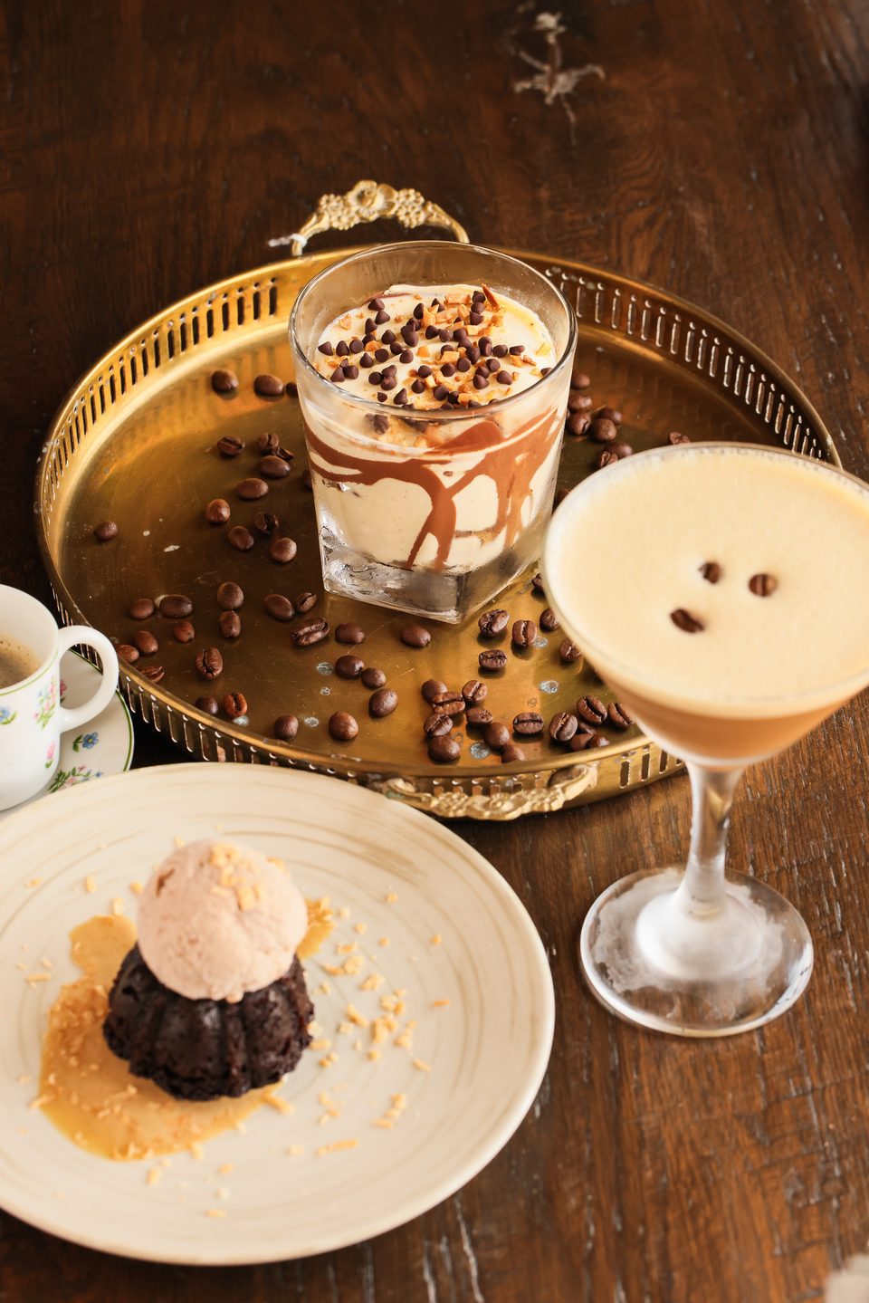 Dessert spread with chocolate lava cake, ice cream, coffee drinks, and coffee beans on a wooden table.